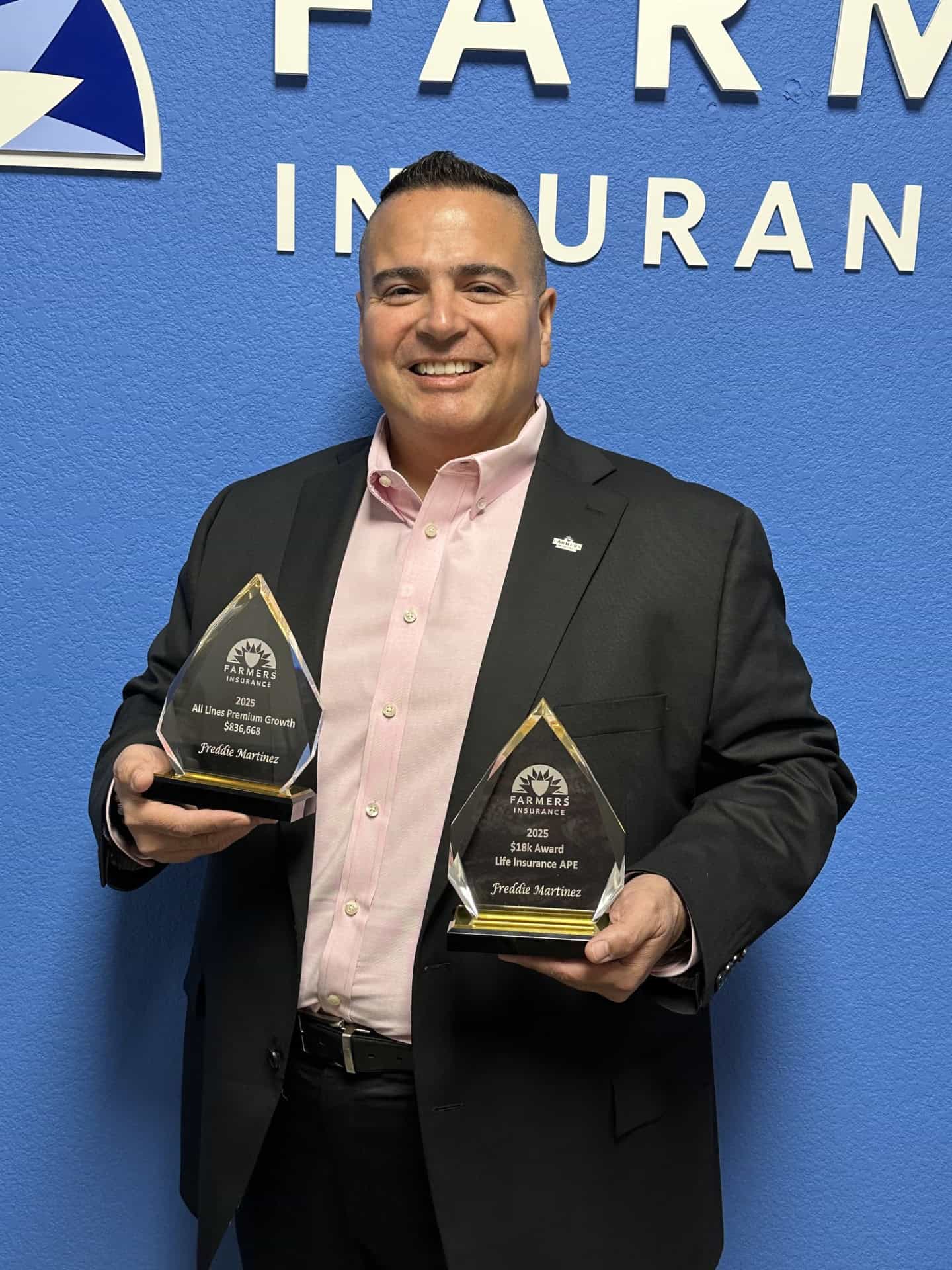 Freddie Martinez holding two Farmers Insurance awards